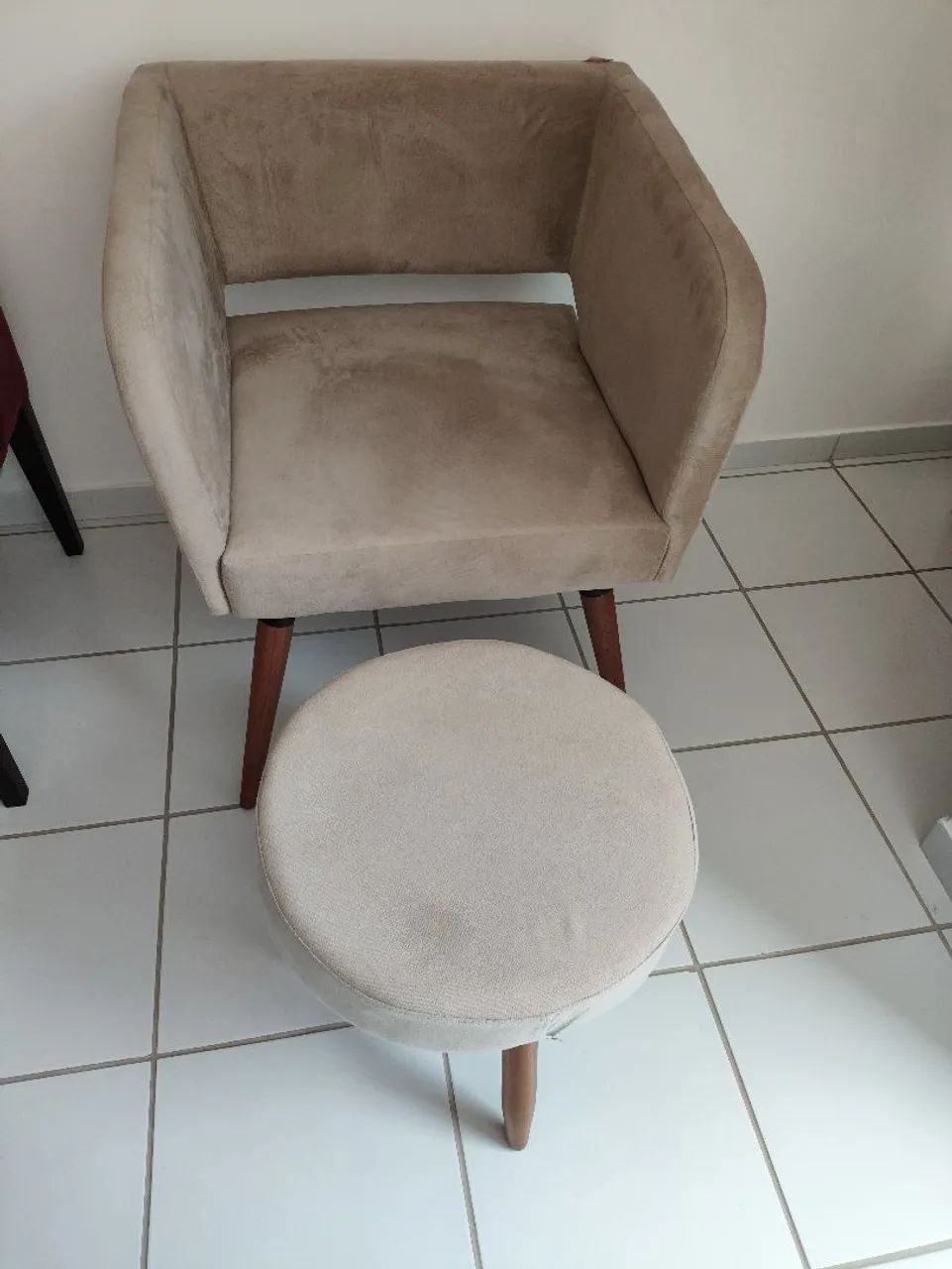 Poltrona bege com banquinho de apoio.