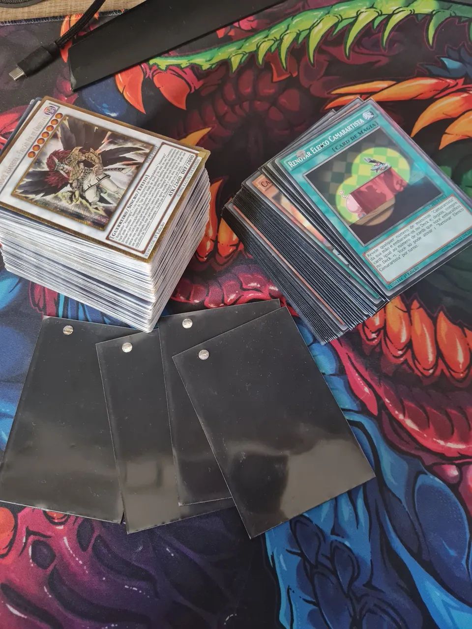 210 Cartas Yugioh diversas e 54 sleeves para proteger as cartas