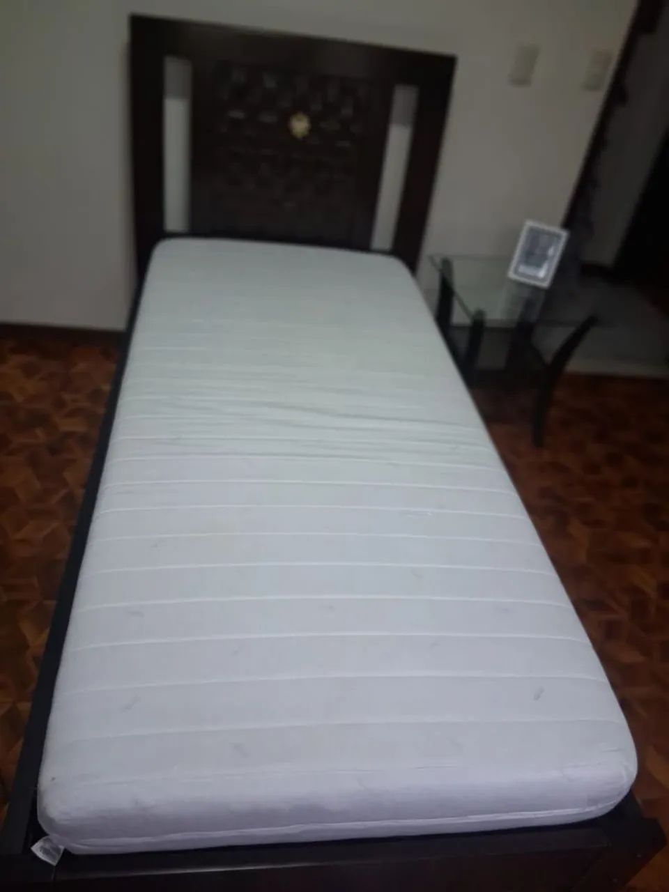 Conjunto de cama, colchão, mesa de cabeceira e cômoda.