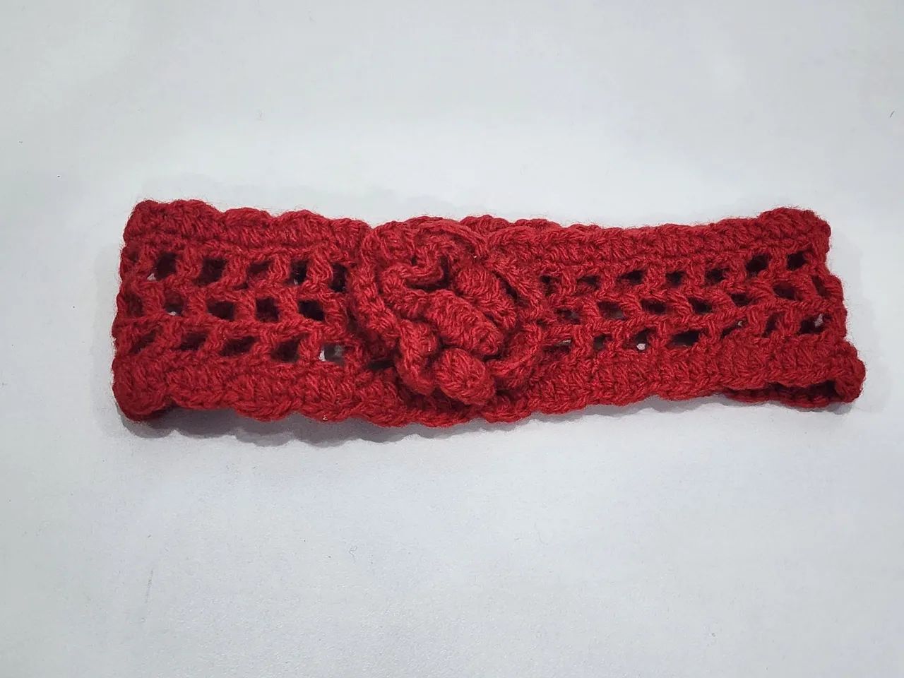 Faixa de crochê vermelha com flor e fechamento por botão 