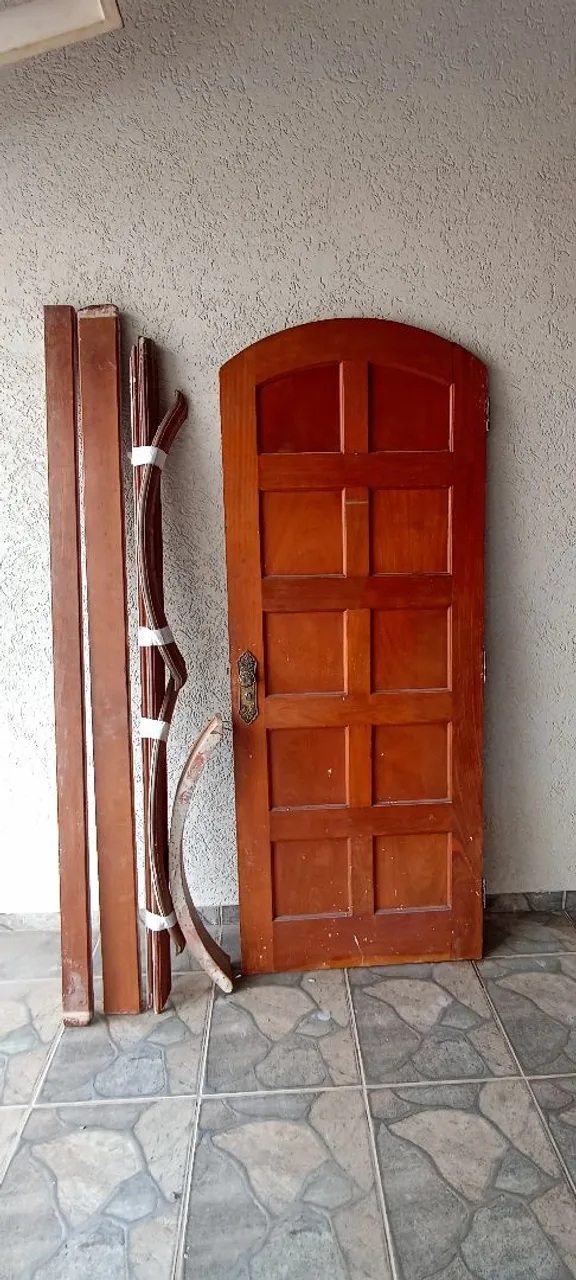 Porta de madeira maciça com batentes e guarnição.