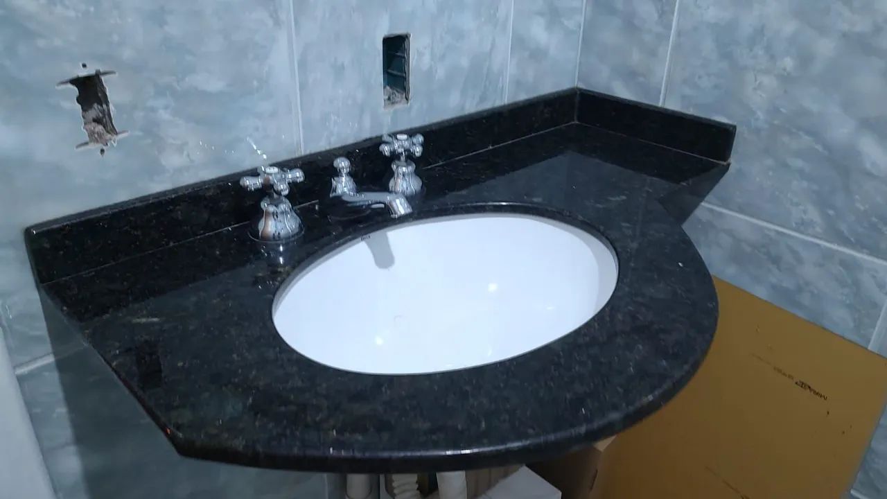 Bancada em granito preto  para banheiro, com cuba branca.