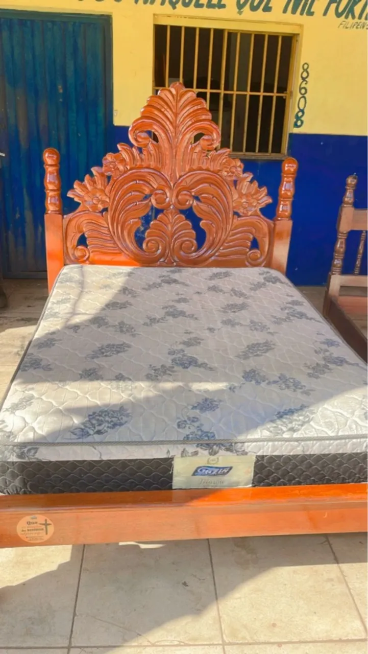 Cama de madeira com cabeceira entalhada e colchão