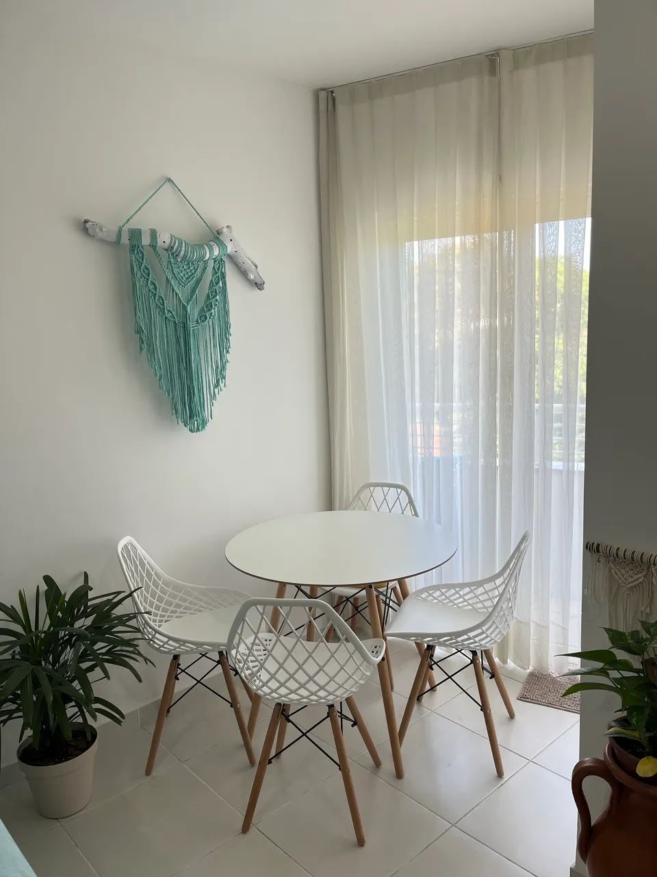 Mesa Eiffel branca com 4 cadeiras vazadas. 