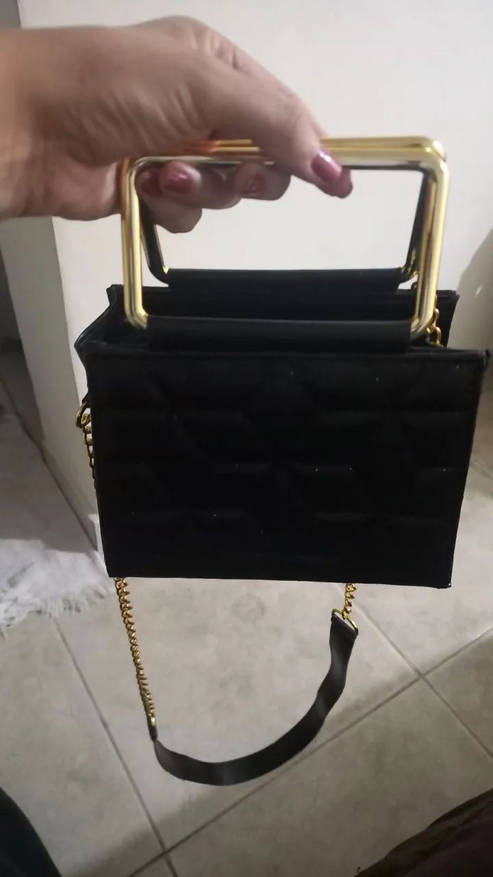 Bolsa preta com alça dourada e corrente