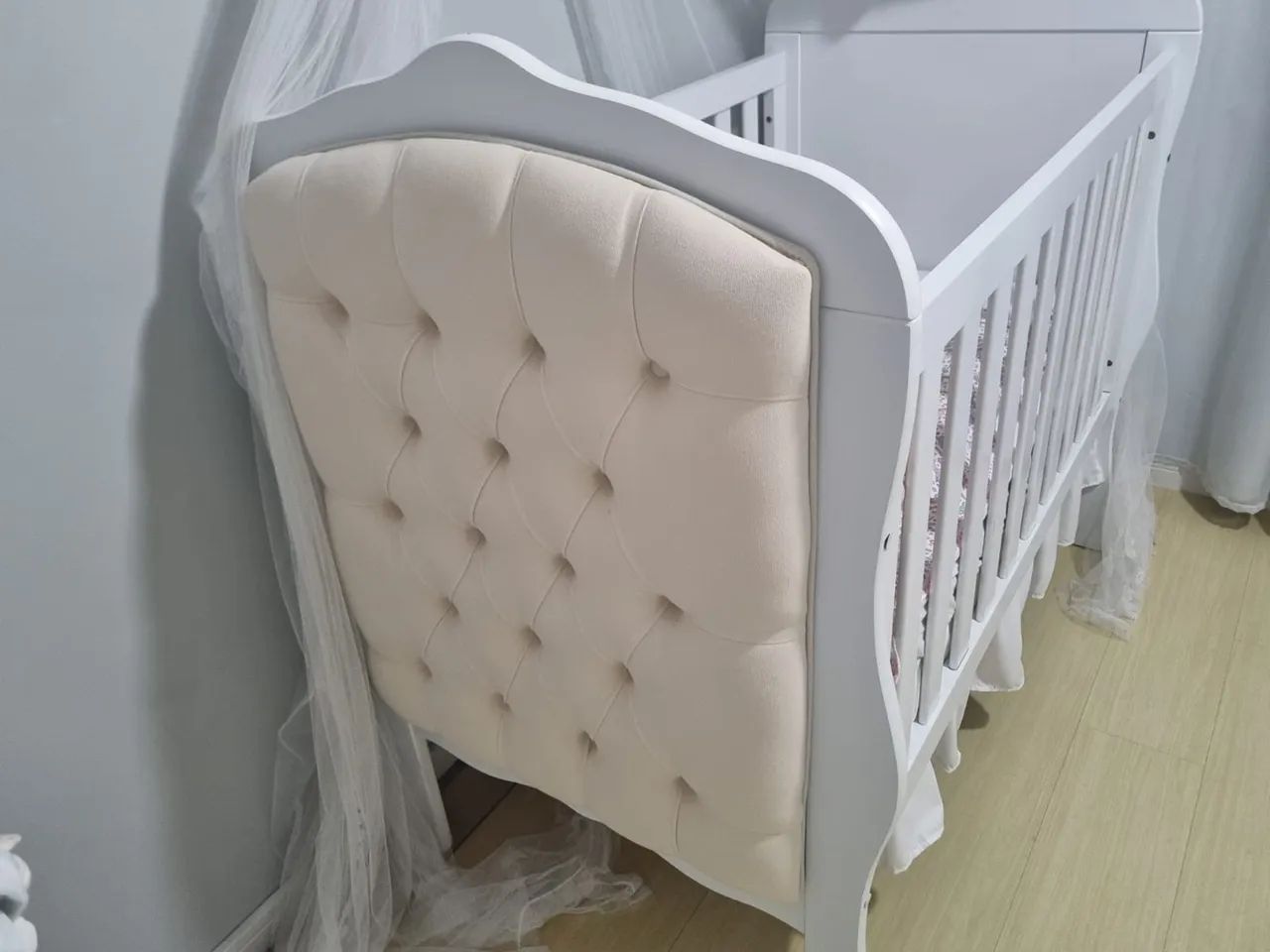 Berço de bebê branco com detalhes em capitonê