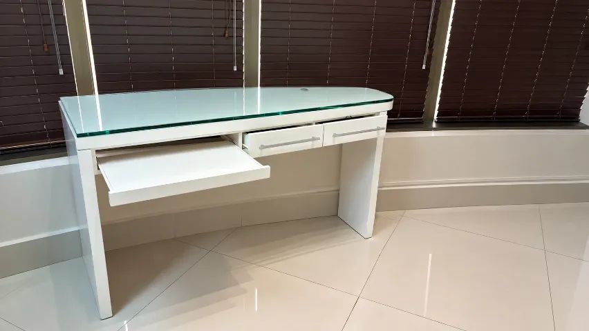 Mesa branca com tampo de vidro, gavetas e bandeja retrátil