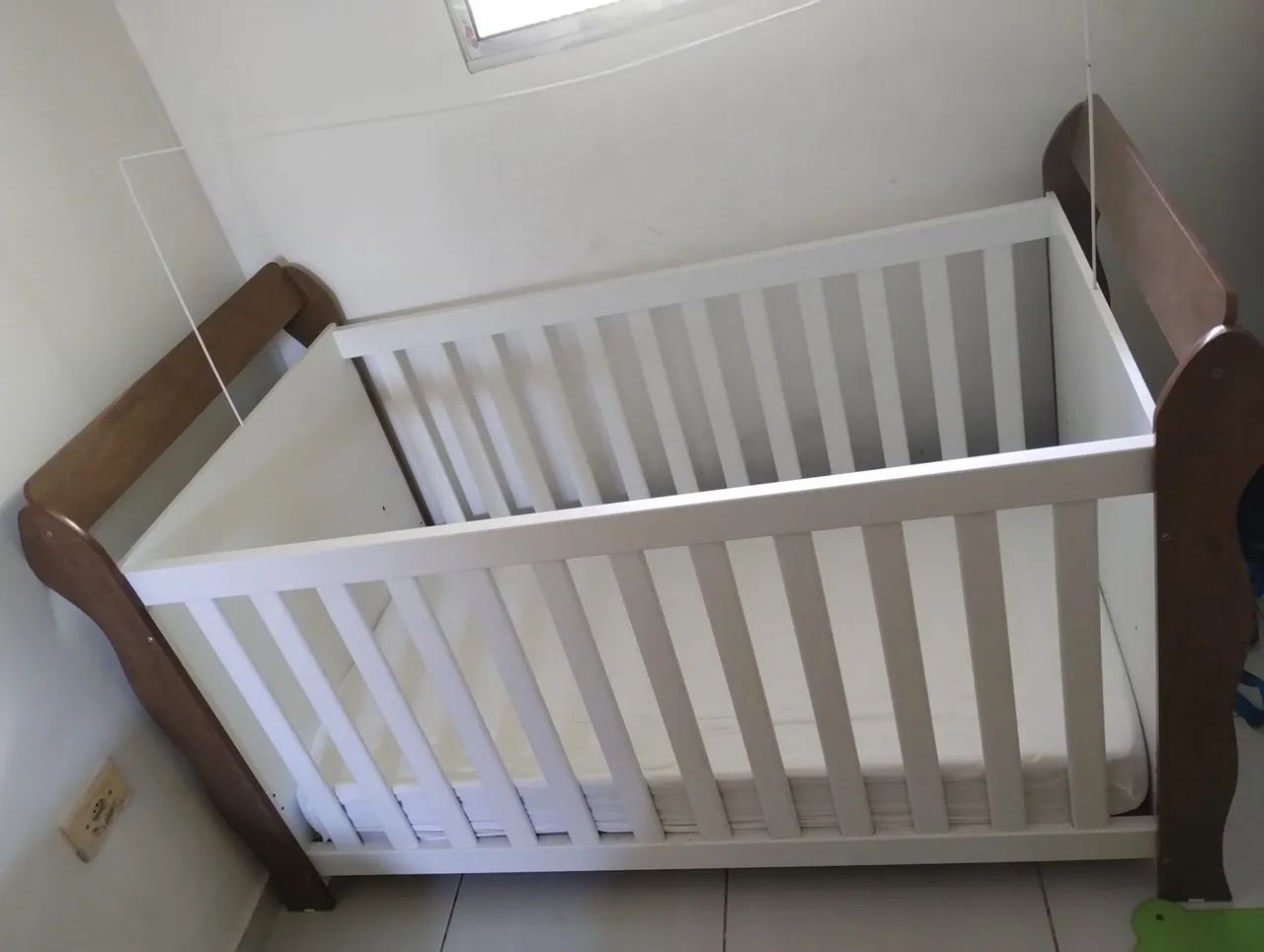 Berço de madeira com detalhes em branco com colchão e mosquiteiro incluso