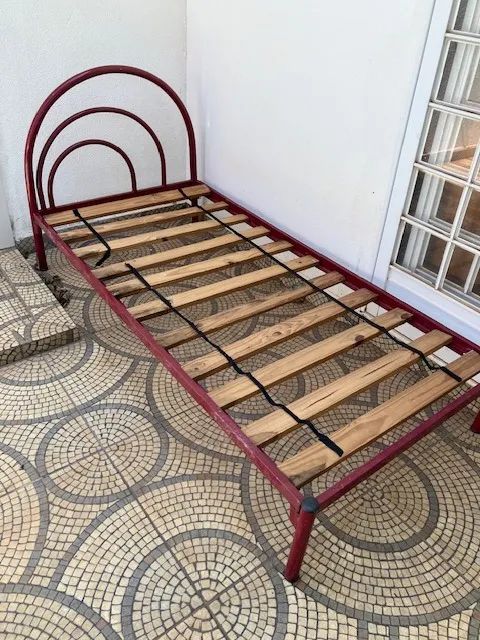 Cama de solteiro de ferro com colchão.