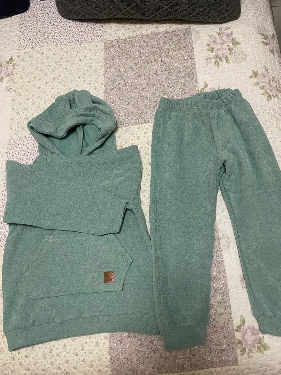 Este é um conjunto de moletom infantil verde com capuz e bolso canguru.
