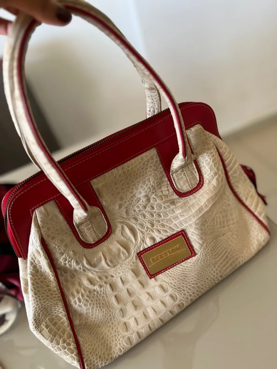 Bolsa de mão em couro com detalhes em vermelho