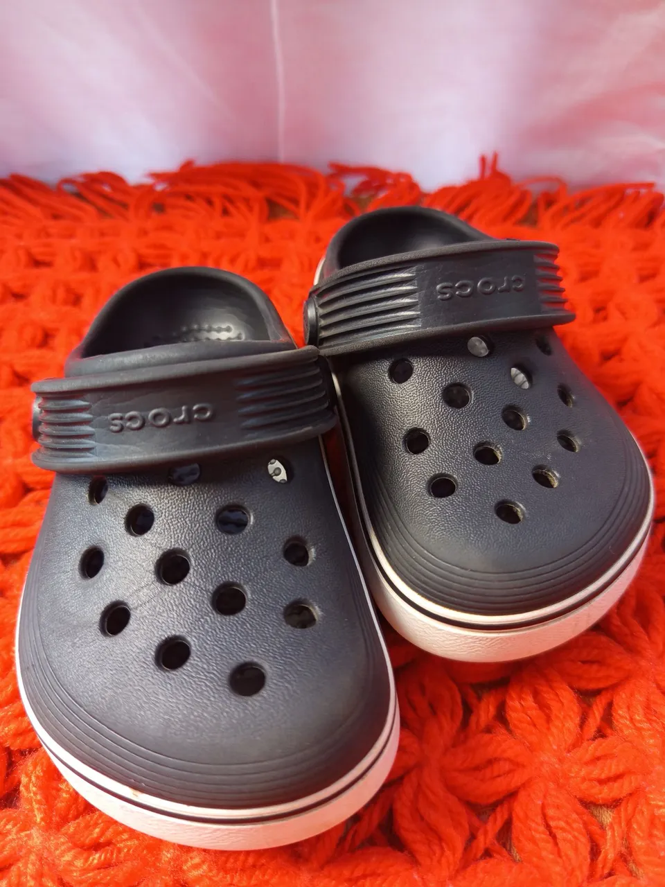 Crocs Infantil Preto com Detalhes Brancos e sapato social azul.