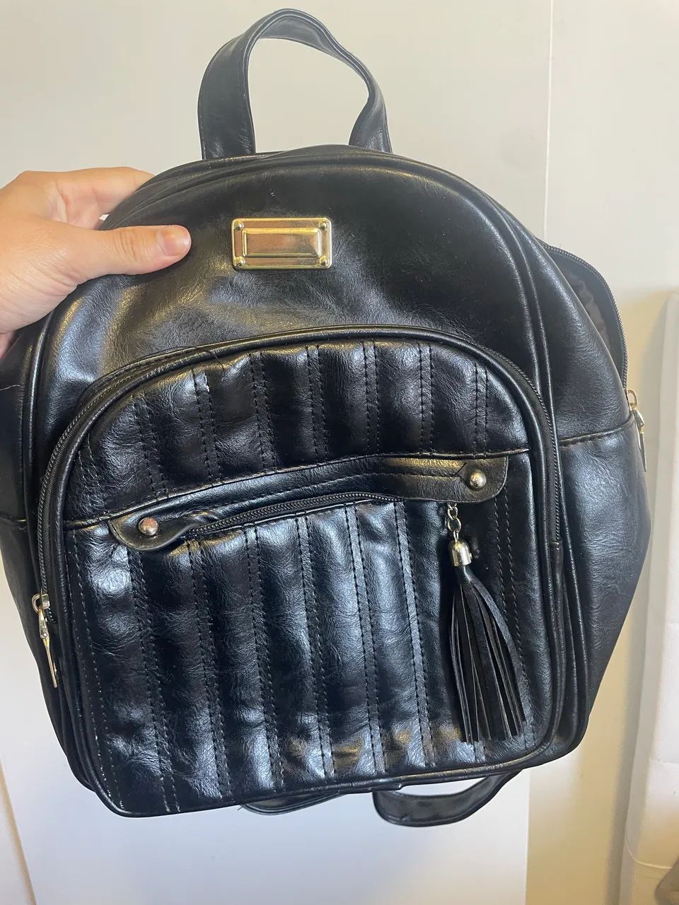Mochila preta em material sintético (couro ecológico) com tassel