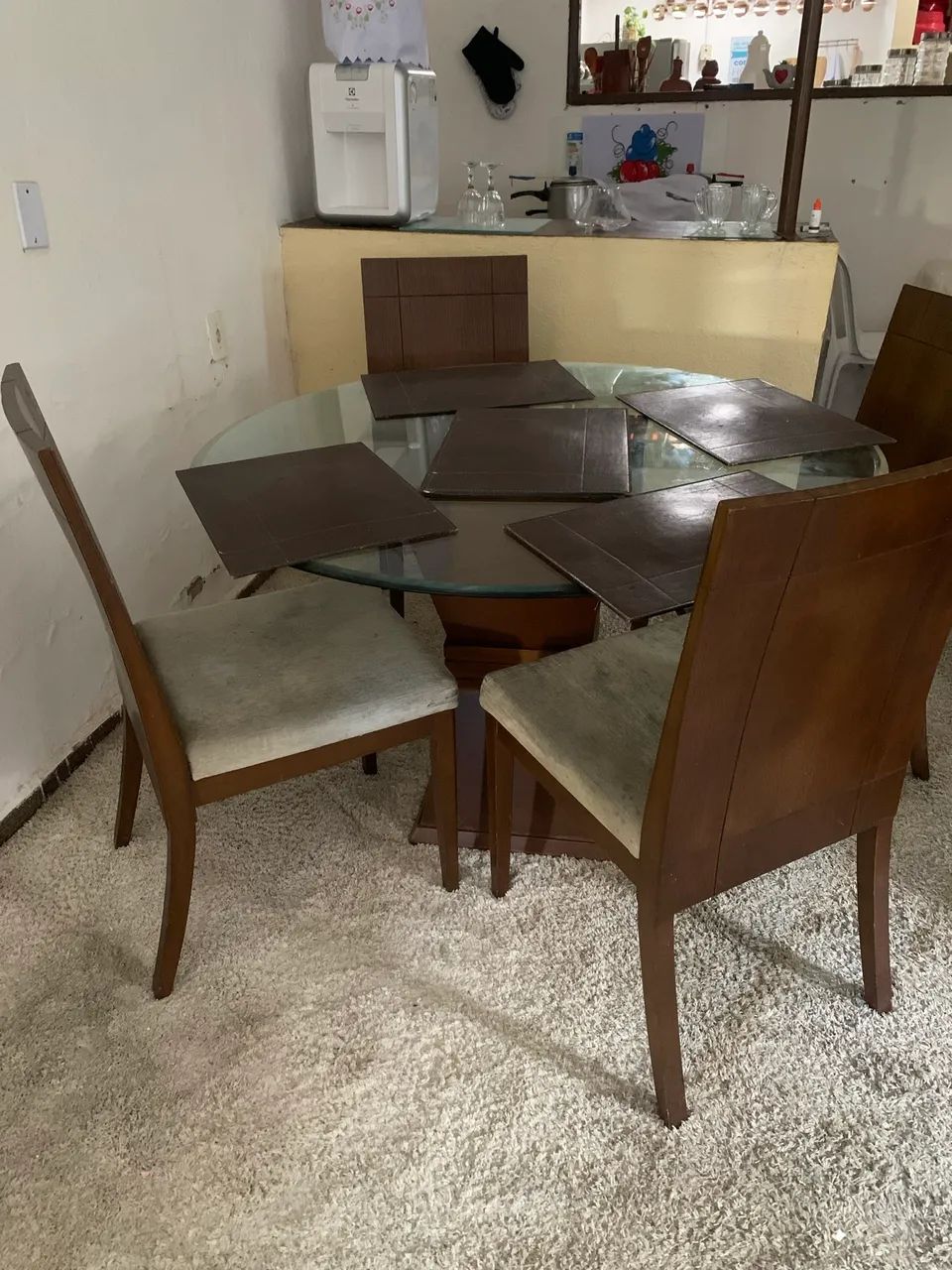 Sala de jantar com tapete, 6 cadeiras e mesa redonda de madeira com tampo de vidro
