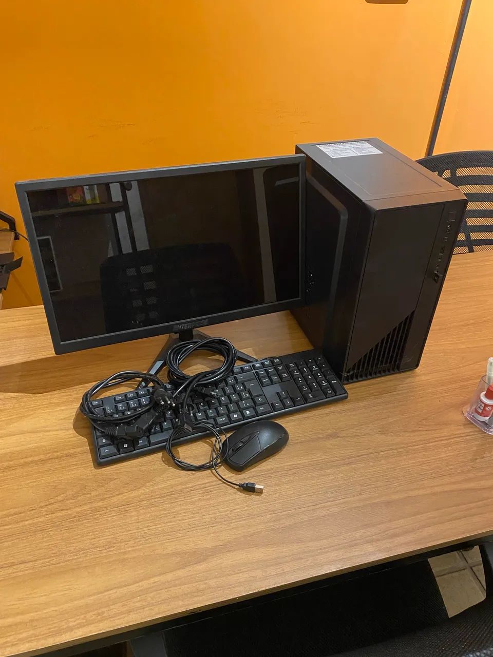 Computador de mesa completo, com monitor, cabos, teclado e mouse.