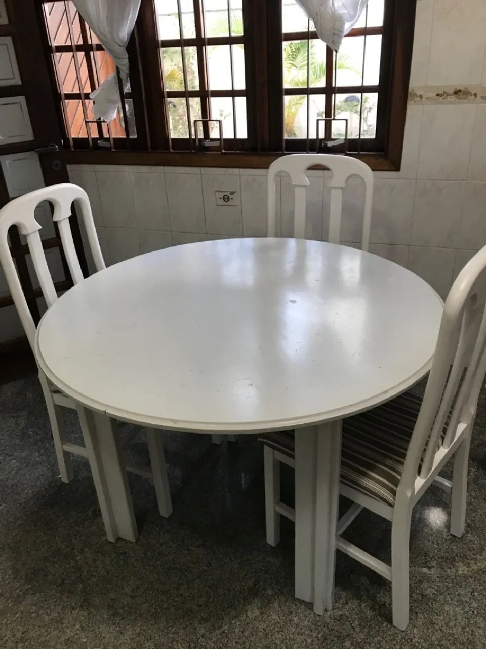 Mesa em madeira redonda com 4 cadeiras estofadas.