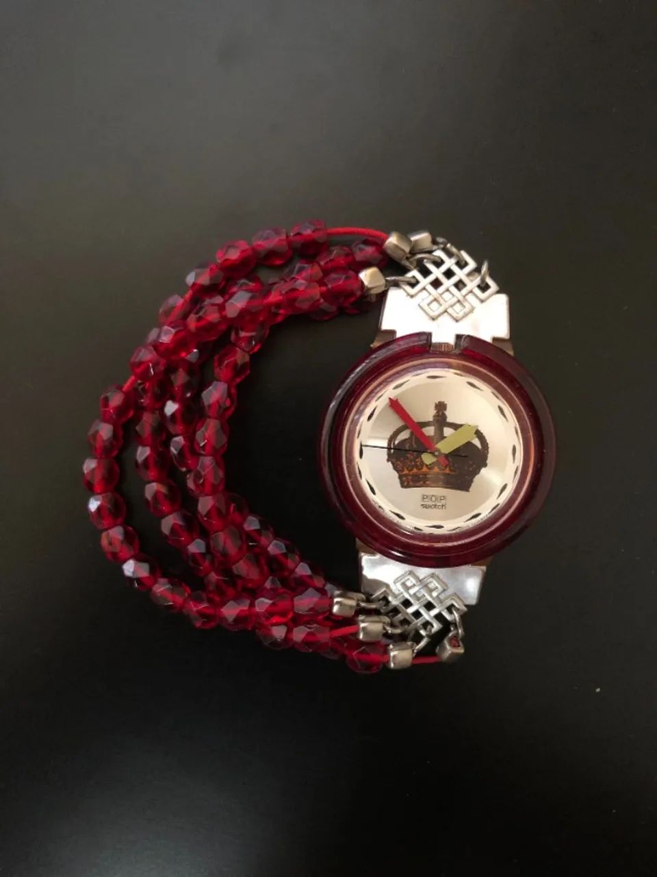 Pop Swatch vintage com coroa no mostrador e pulseira de contas vermelhas.