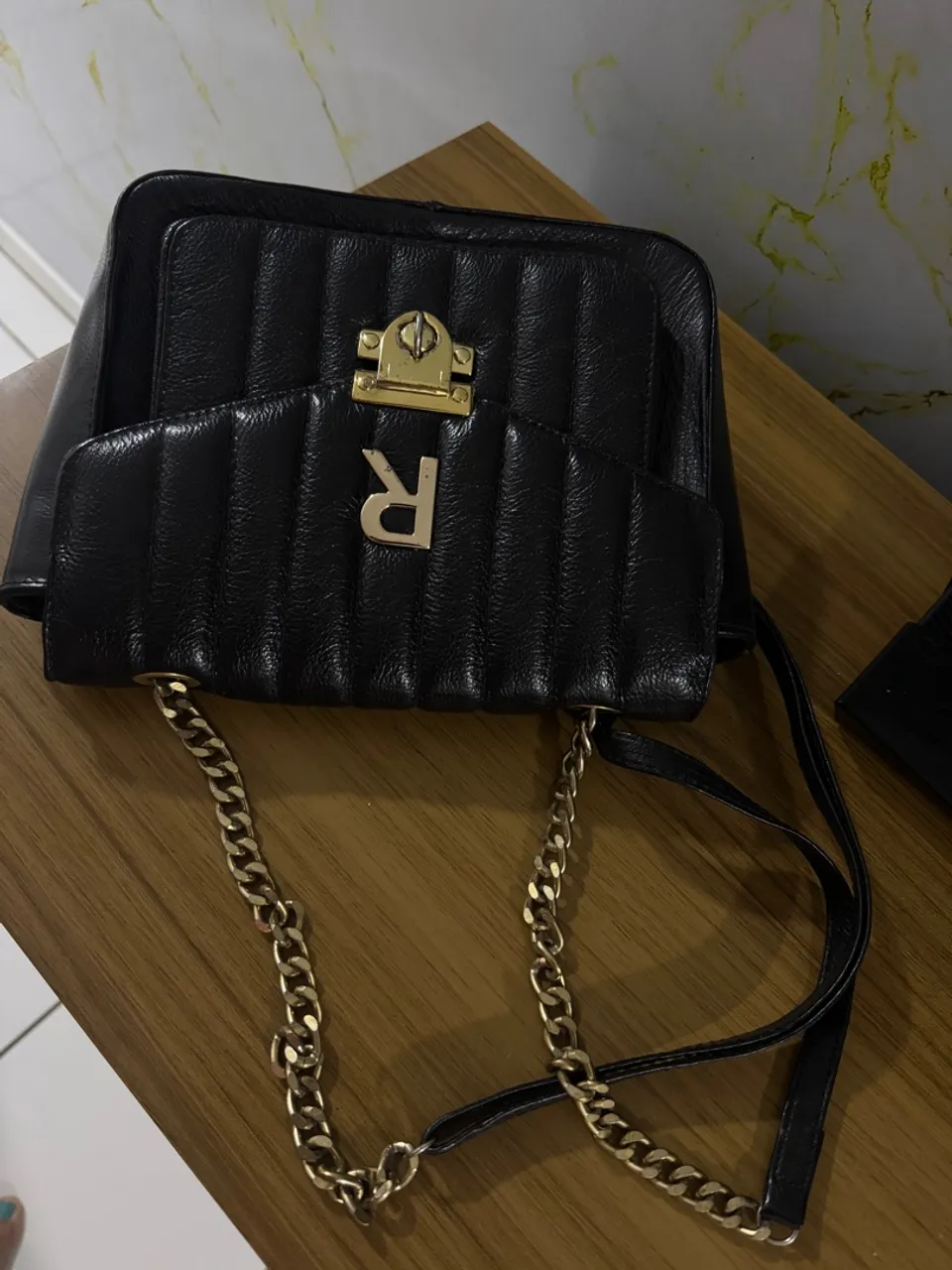 Bolsa preta com corrente e detalhe em dourado