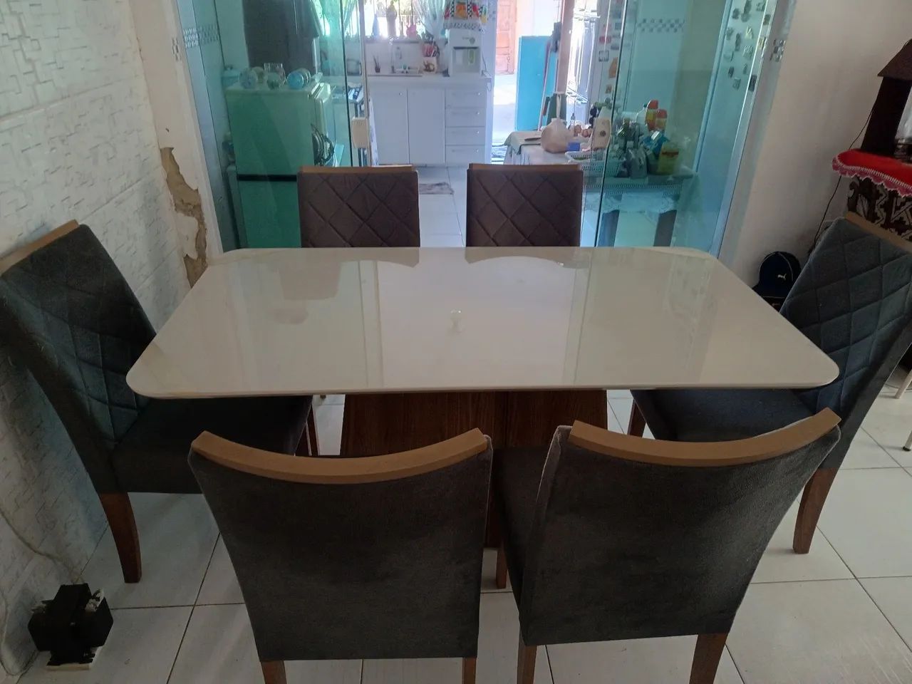 Mesa de jantar com seis cadeiras forradas e macias.