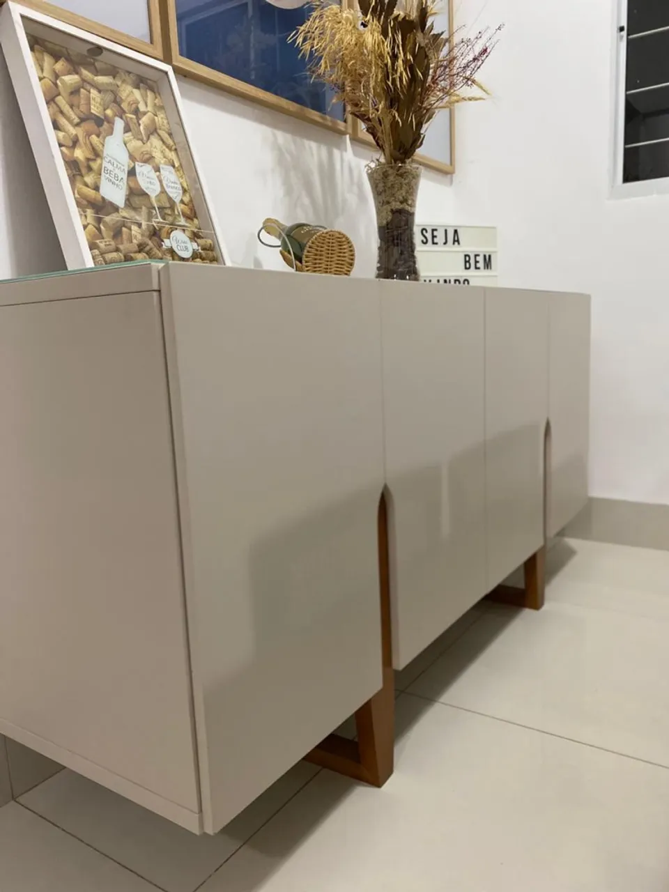 Buffet moderno offwhite com detalhes em madeira e tampo de vidro.