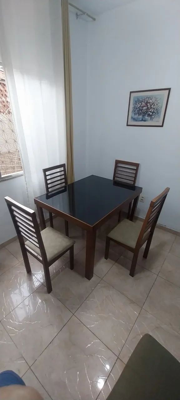 Mesa com quatro cadeiras em madeira com tampo de vidro. 