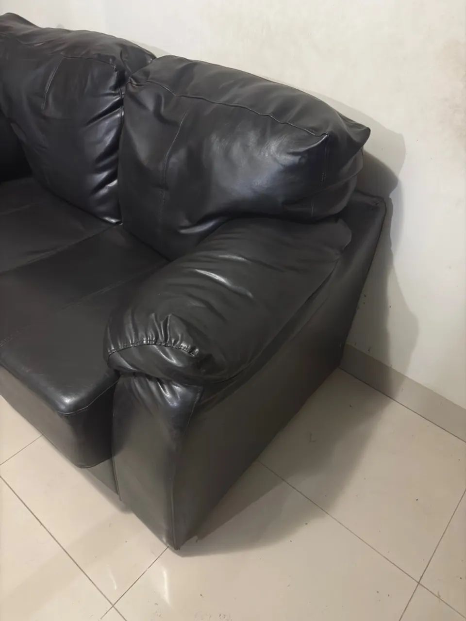 Sofá de Couro Preto e uma mesa para apoiar o pé ou decorar com algo