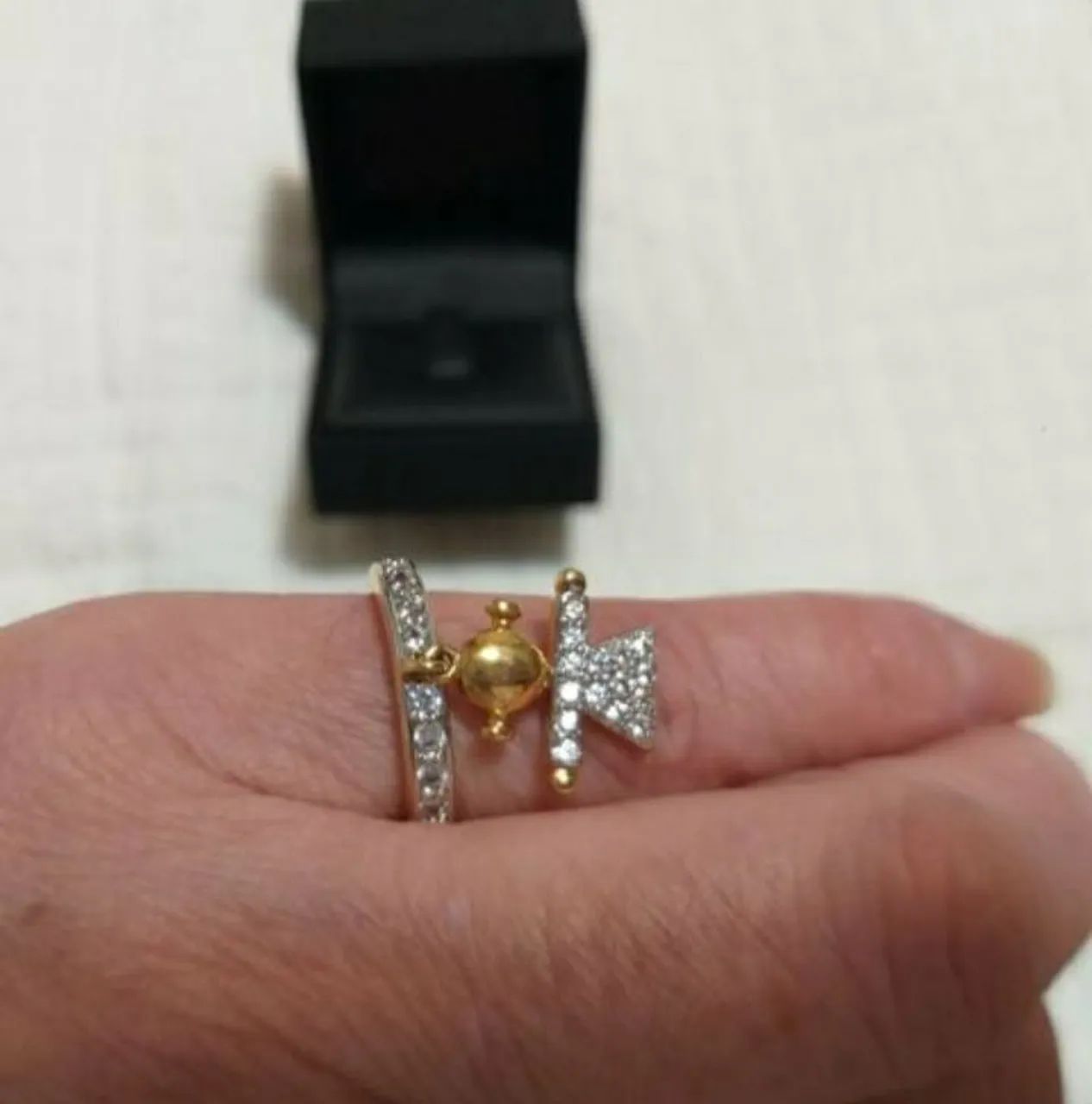 ANEL COM PINGENTE "MENINA", COM CRISTAIS E BANHADO A OURO, MARCA ATTRATTIVA.