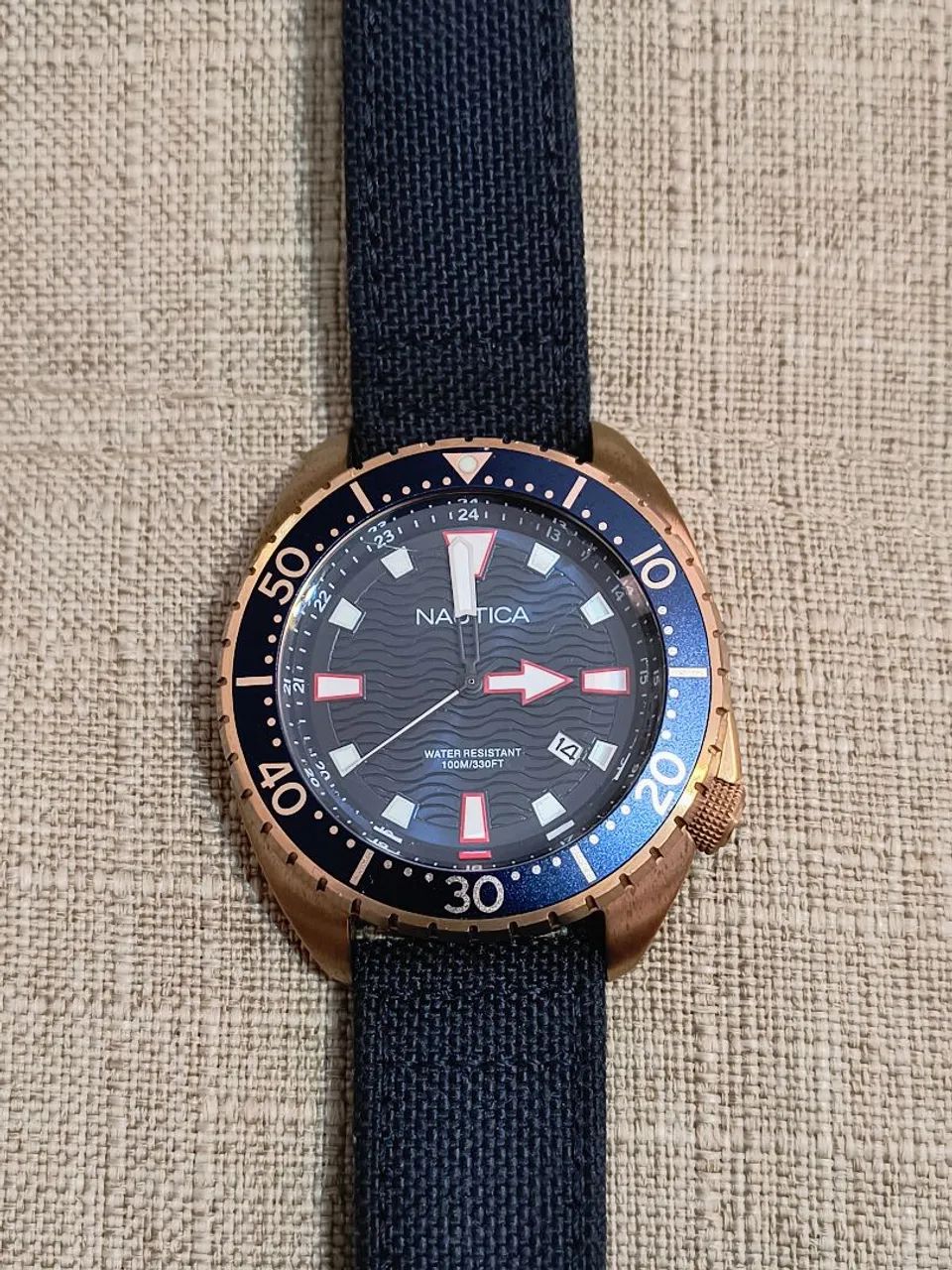Relógio Nautica dourado fundo azul, pulseira nylon/couro.<br><br>