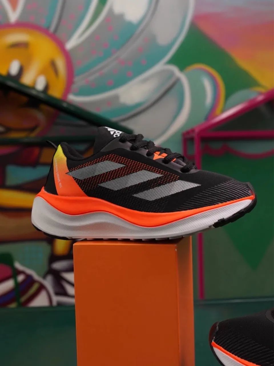 Tênis esportivo adidas com detalhes laranja 