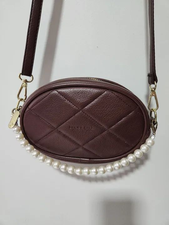 Bolsa Oval Lateral com pérolas Lucky Girl, cor marron, zíper central e alça regulável.