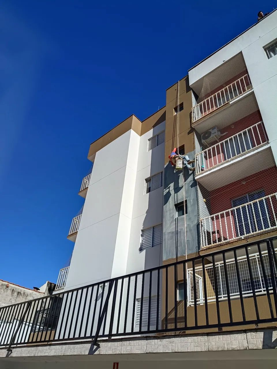 Pintura de prédios com cadeira suspensa 