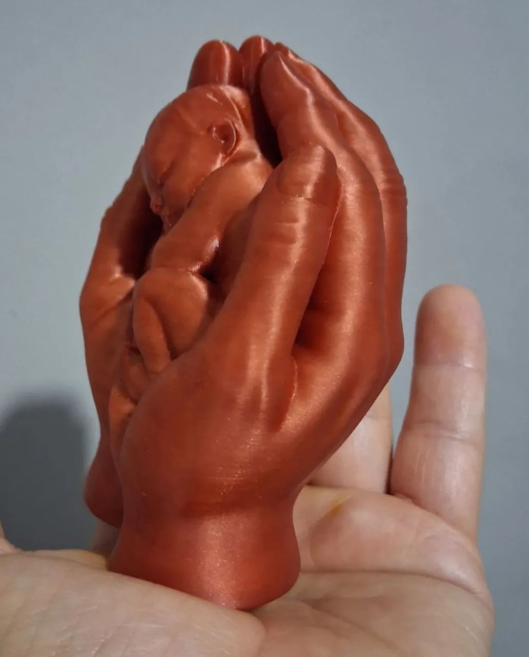 escultura mãos segurando bebê na cor cobre - Foto 2