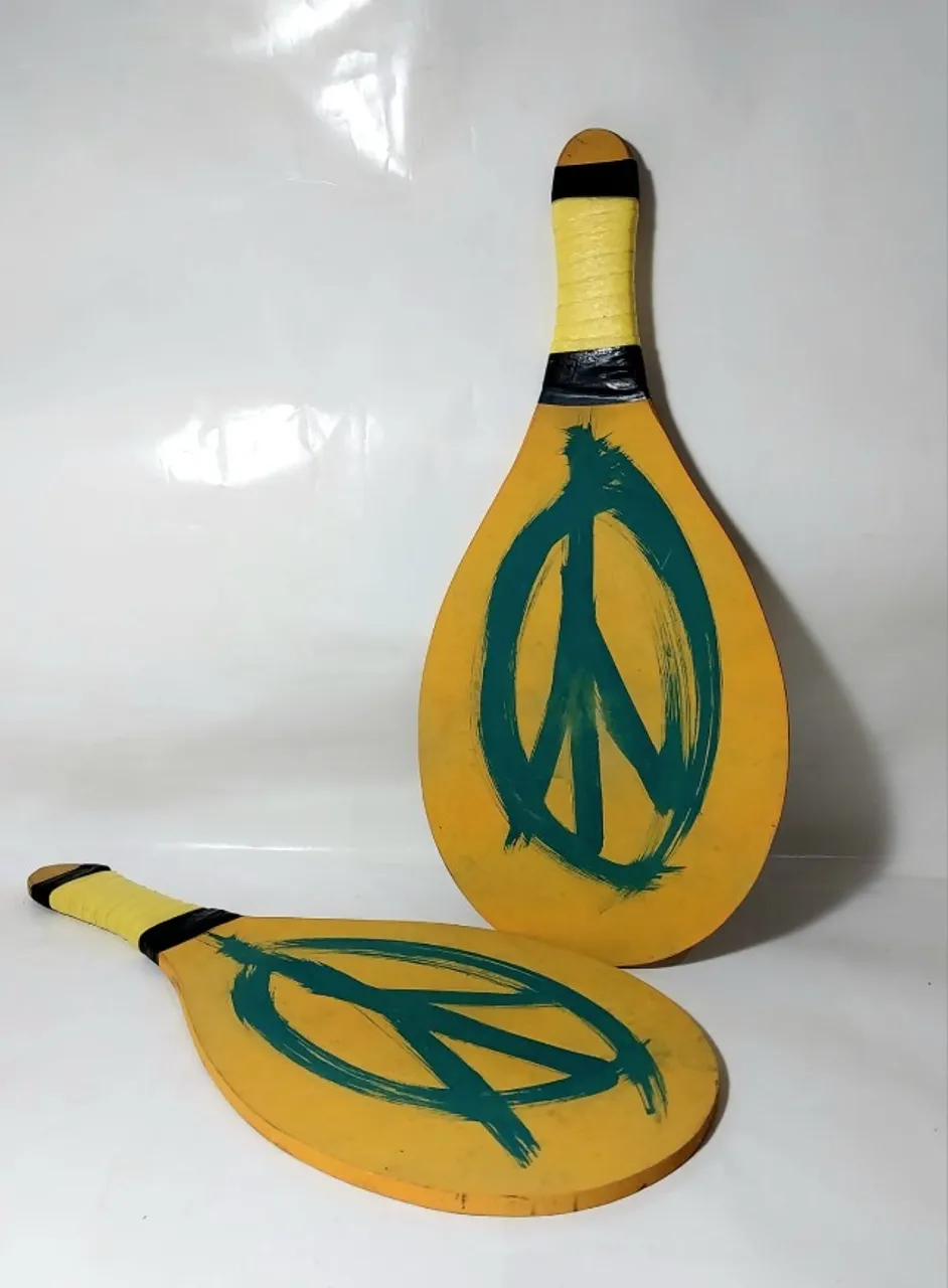 2 RAQUETES FRESCOBOL - SEM USO MDF COR AMARELO COM GRAFISMO SIMBOLO DA PAZ EM VERDE,
