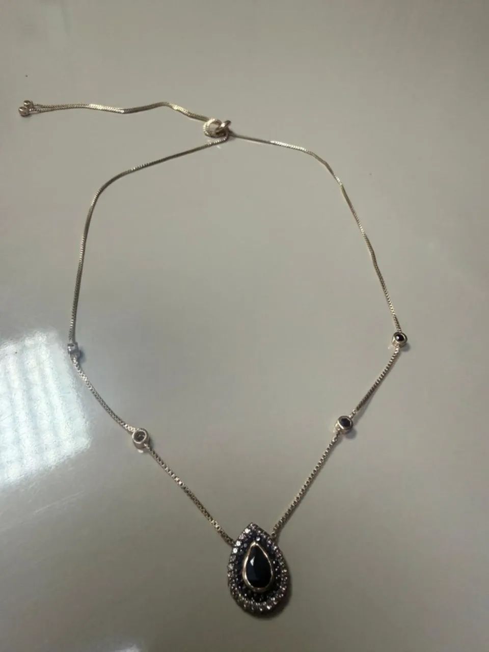 Colar estilo gravatinha com pingente escuro e pedras