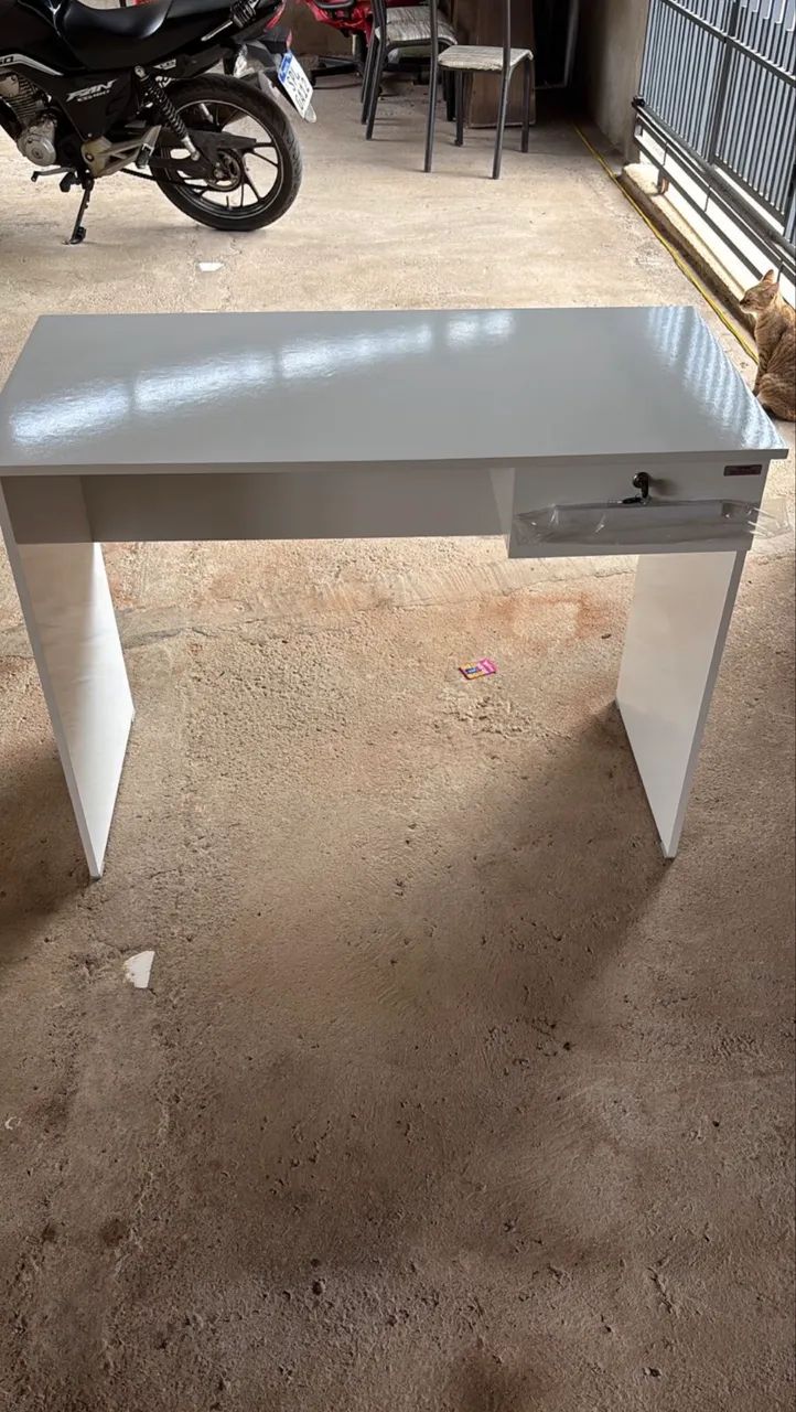 Mesa de escritório branca com gaveta e chave.