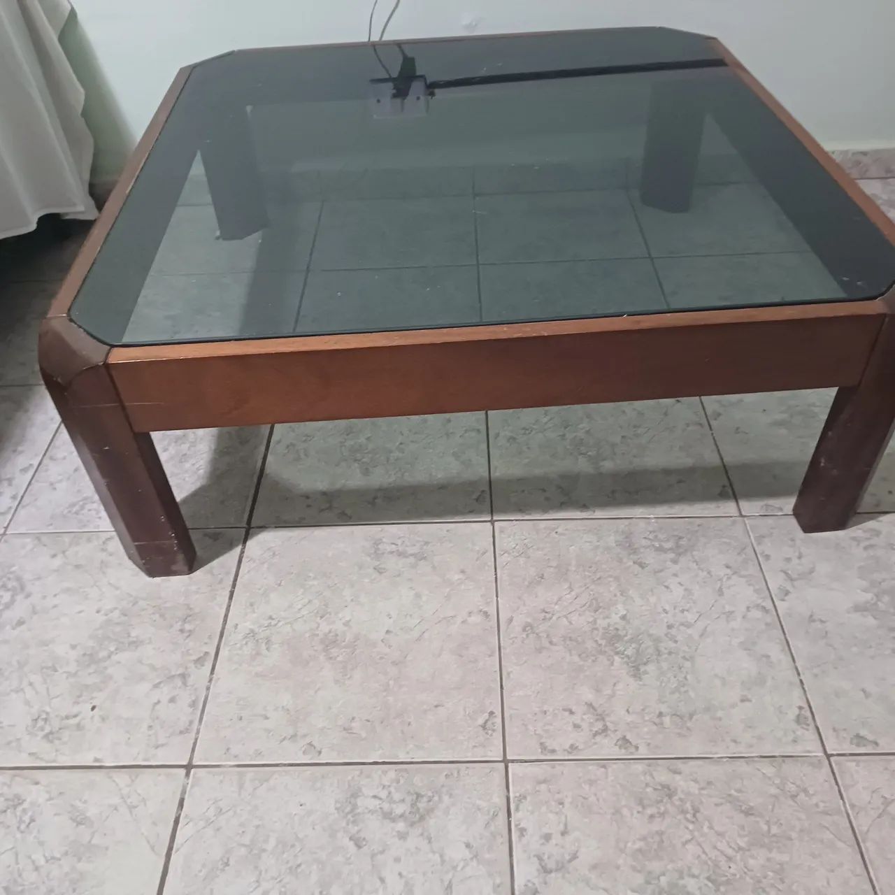 Mesa de centro em madeira com tampo de vidro e mesas laterais.