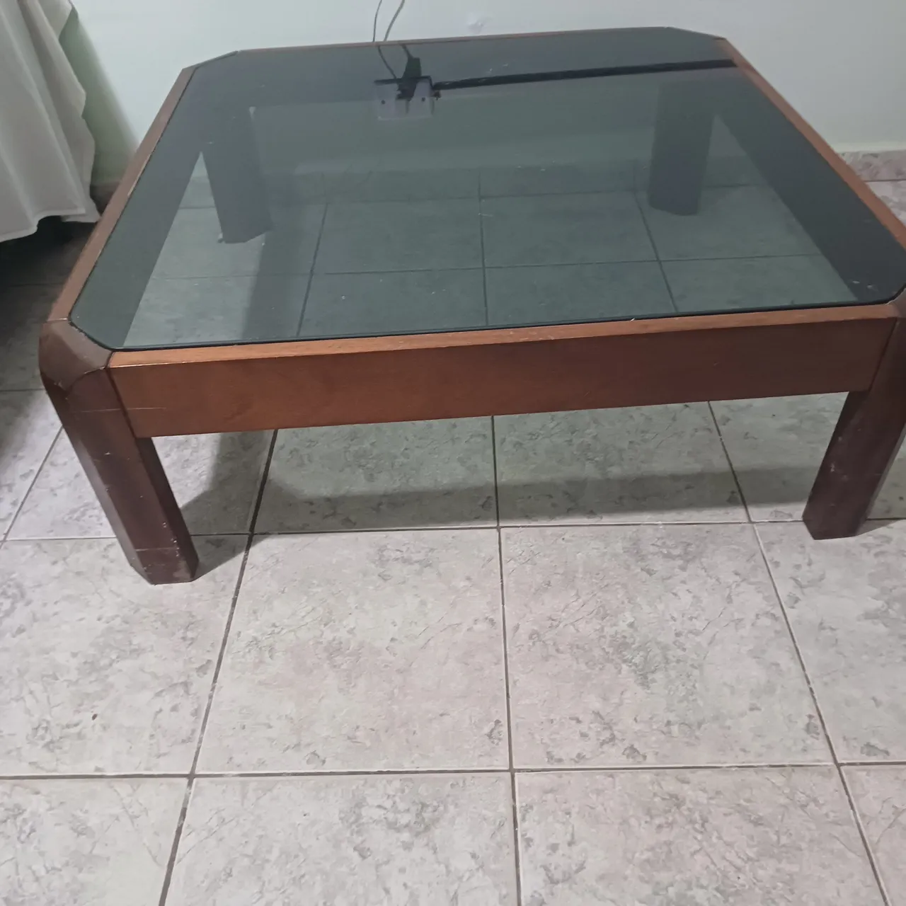 Mesa de centro em madeira com tampo de vidro e mesas laterais.