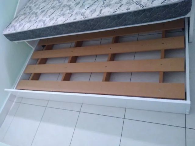 Cama auxiliar branca de MDF com colchão.