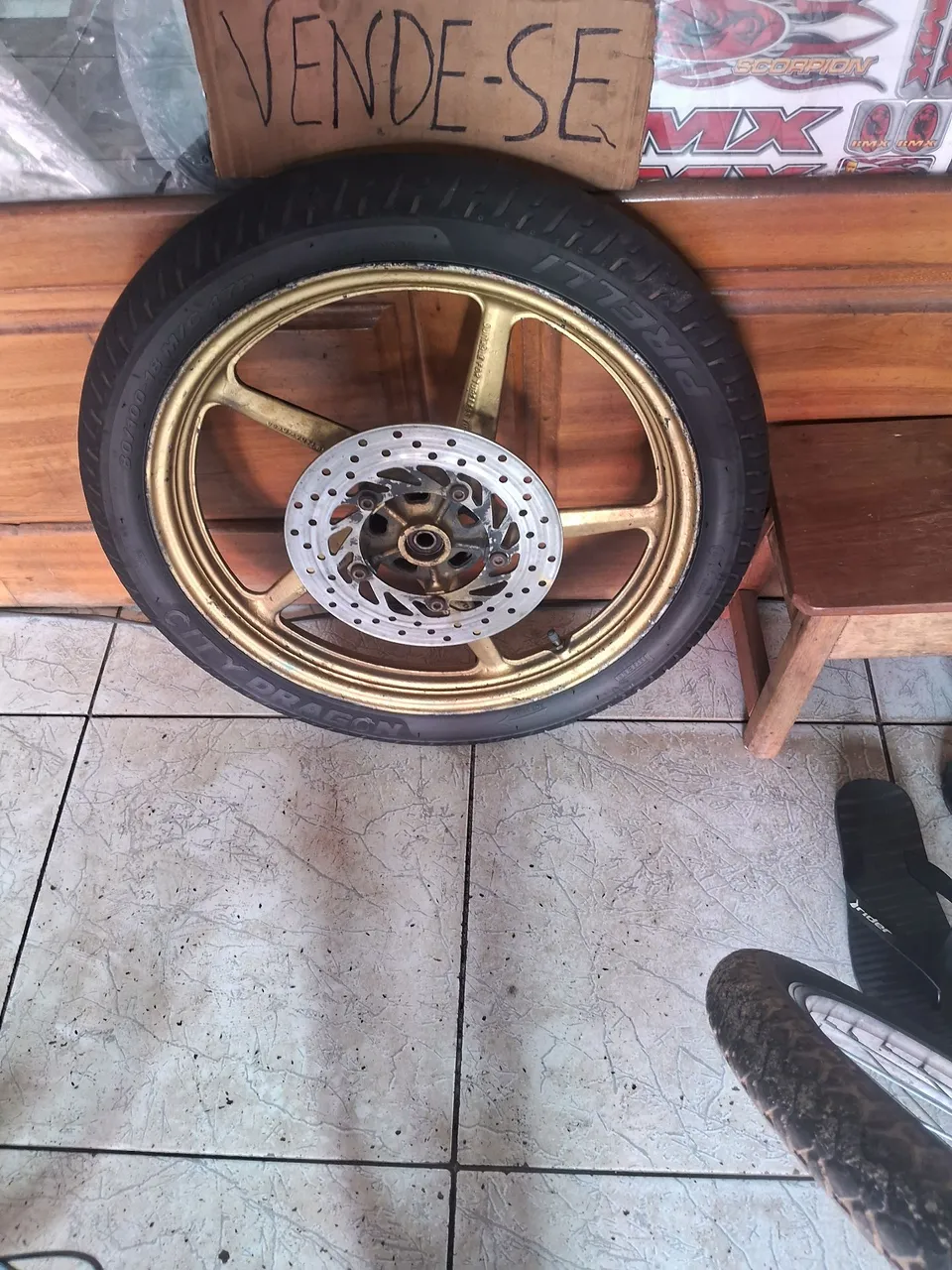Roda de moto dourada com pneu e disco de freio