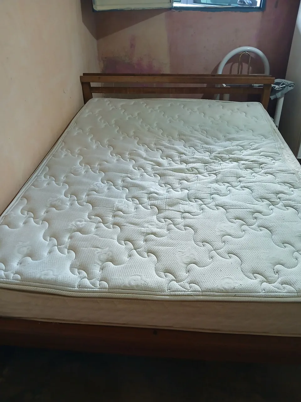Uma cama de madeira e um colchão de casal em perfeito estado
