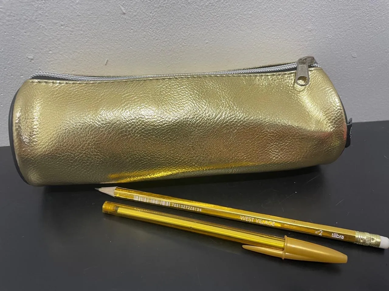Estojo escolar dourado e uma caneta e um lápis