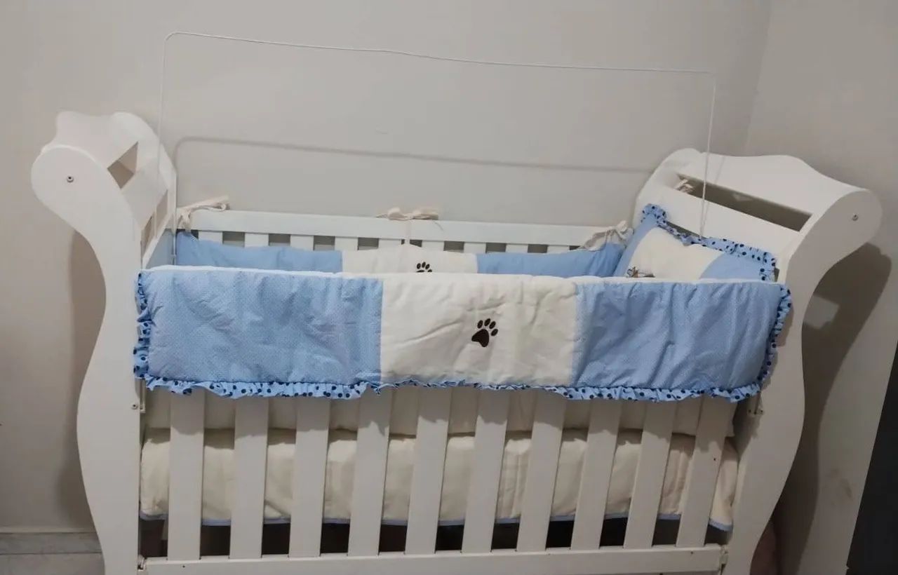 berço de madeira branco com um kit de berço 