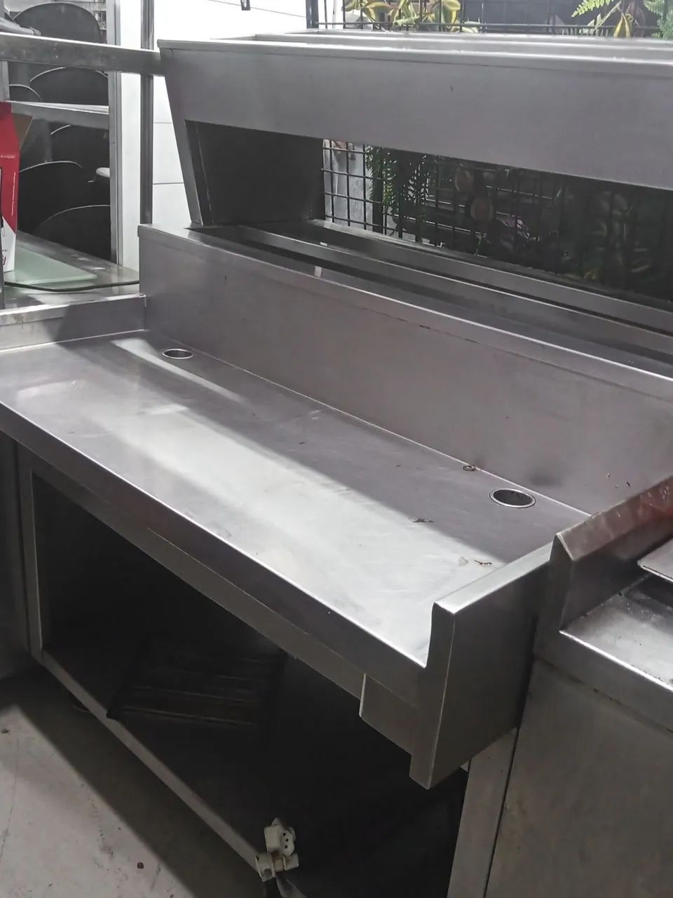 Stainless steel counter with two refrigerated condiment dispensers and equipment support table with power outlets