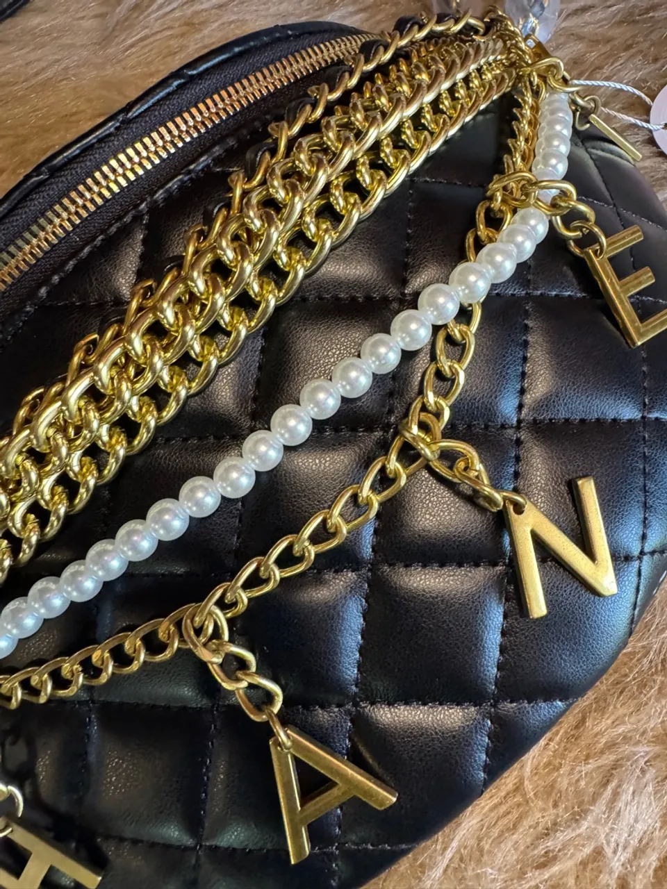 Bolsa preta com detalhes dourados e corrente