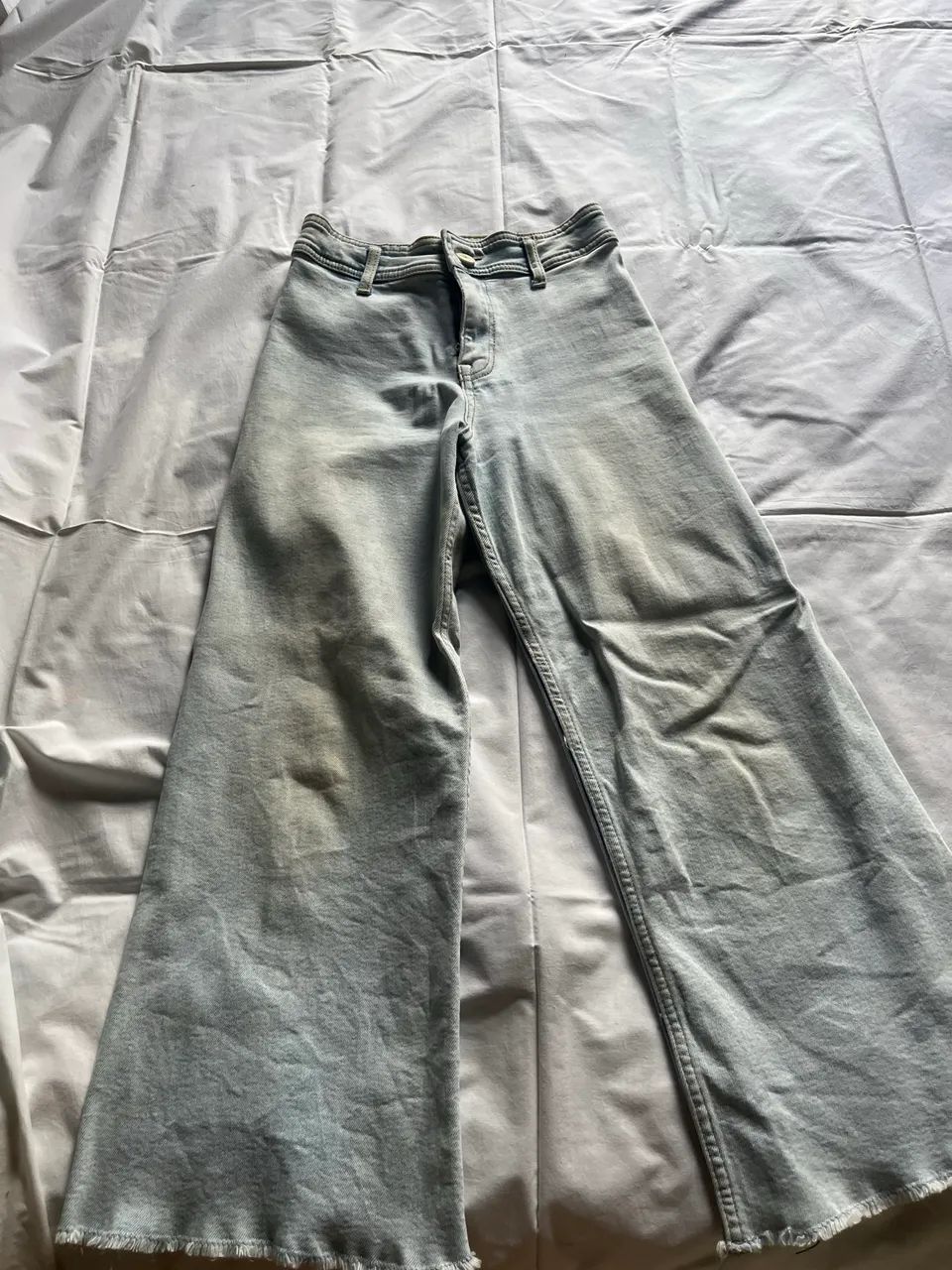 Calça jeans clara desfiada na ponta 