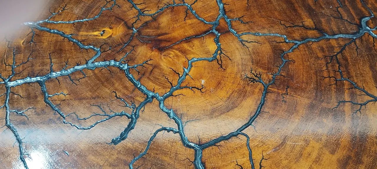 Mesa de centro eletrificada em madeira maciça e resina com veios pretos.