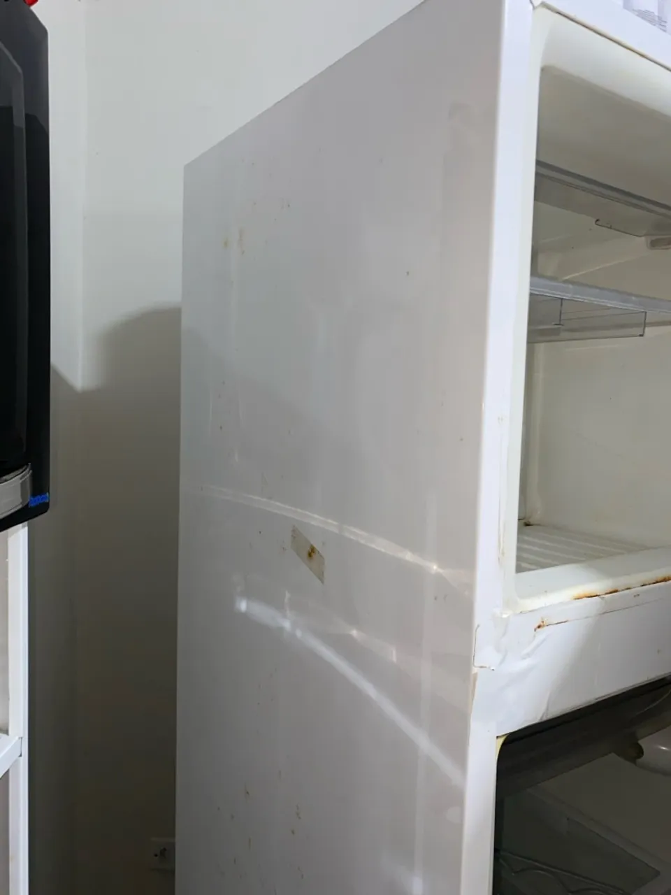 Geladeira branca com marcas de uso