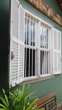 Janela de madeira com grade e veneziana