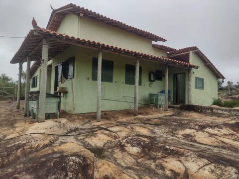 Sítio com casa construída sobre a rocha e em área bem verde.