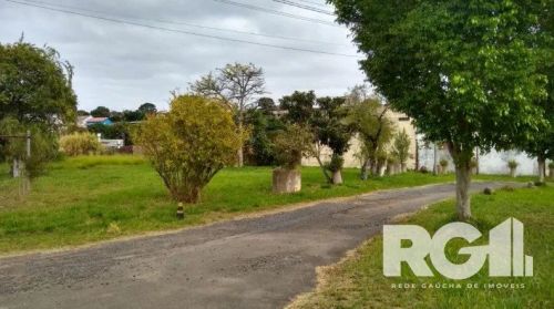 Terreno totalmente plano e cercado com um único portão de entrada. Está limpo, com árvores